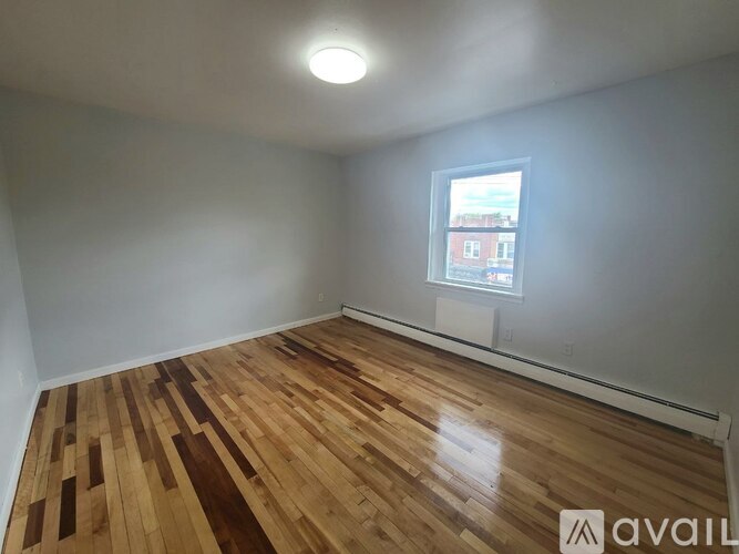 A room with wooden flooring and a window showing a view of a building outside.