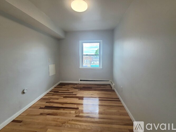 A room with wooden flooring and a window.