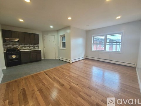 A room with wooden flooring and a window overlooking a red building.