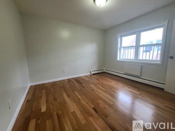 A room with wooden flooring and a window.