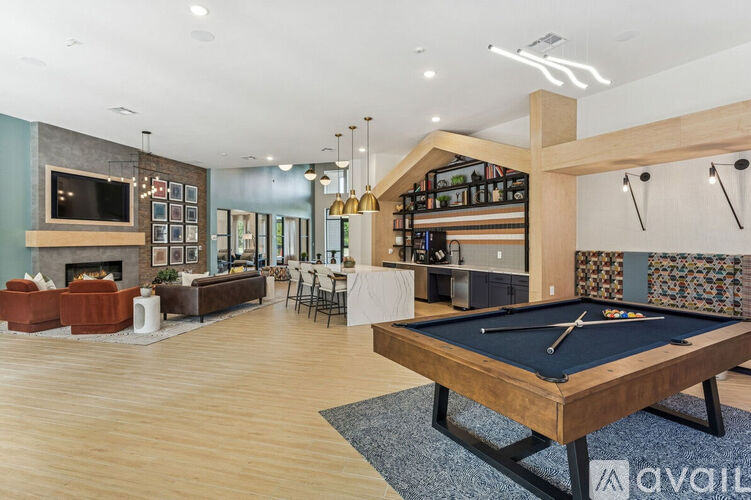 A pool table is in the middle of a room with a fireplace and a bar area.