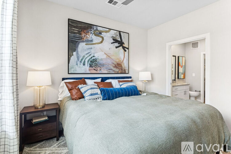 A bedroom with a large bed and a painting on the wall.
