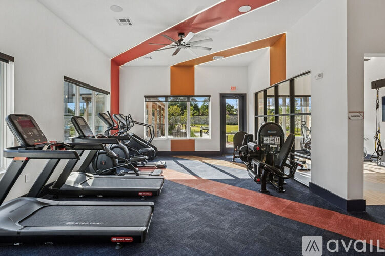 A gym with treadmills, elliptical machines, and a fan.