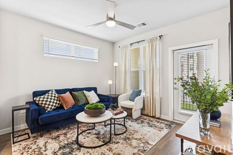 A living room with a blue couch and a rug.