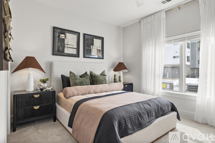 A bedroom with a large bed, two lamps, and pictures on the wall.