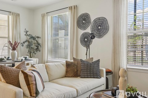 A living room with a white couch and a large window with blinds.
