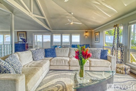 A living room with a large sofa and a glass coffee table.
