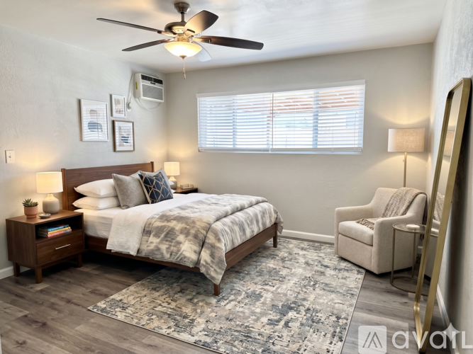 A bedroom with a bed, chair, and ceiling fan.
