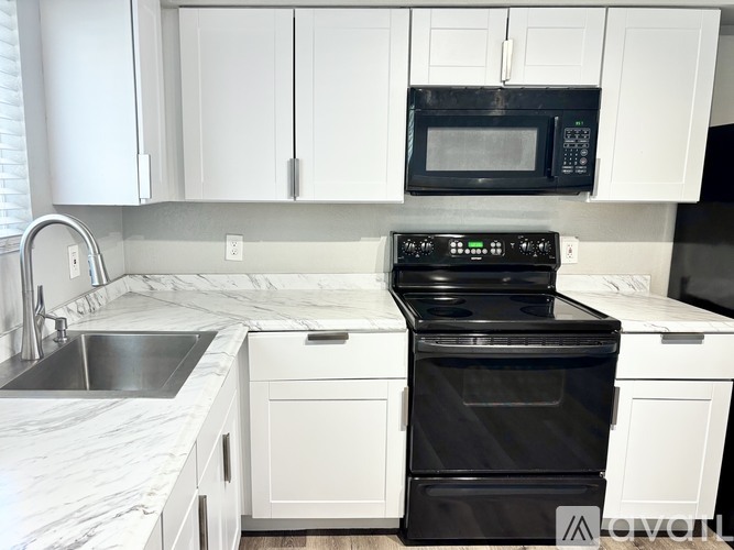 A black stove top oven sits in a kitchen with white cabinets.