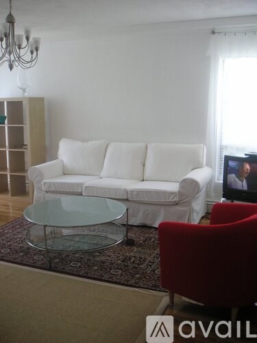 A white couch sits in a living room with a glass coffee table in front of it.