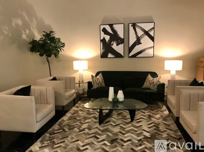 A living room with a black couch, white chairs, and a patterned rug.