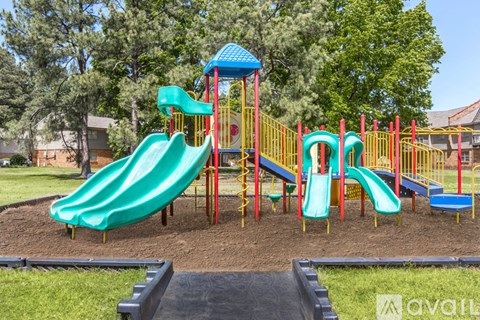 A playground with a green slide and a blue and yellow structure.