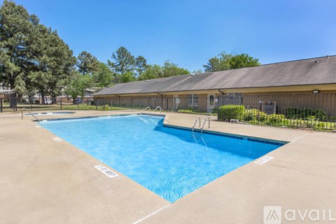 A large outdoor swimming pool with a diving board and a building in the background.