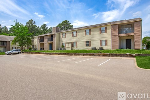 A parking lot in front of a row of apartment buildings.