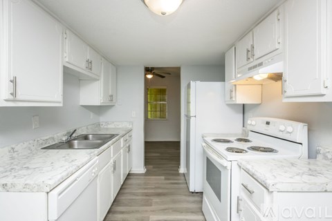 A kitchen with white cabinets and a marble countertop.