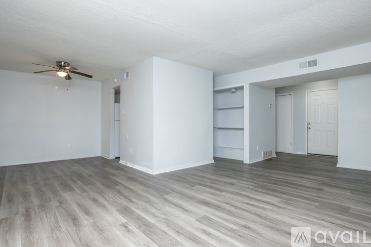 A spacious room with a ceiling fan and wooden flooring.
