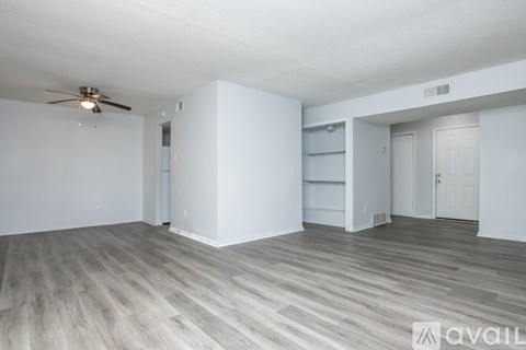 A spacious room with a ceiling fan and wooden flooring.