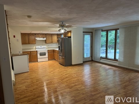 A spacious kitchen with wooden floors and a refrigerator.