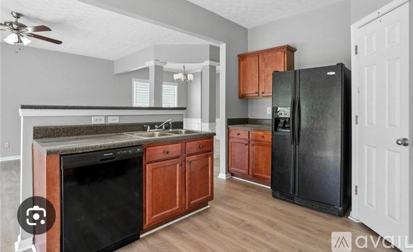A kitchen with a black fridge and wooden cabinets.