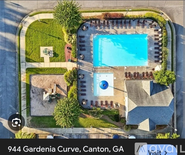 An aerial view of a swimming pool surrounded by a grassy area and a building with a blue roof.