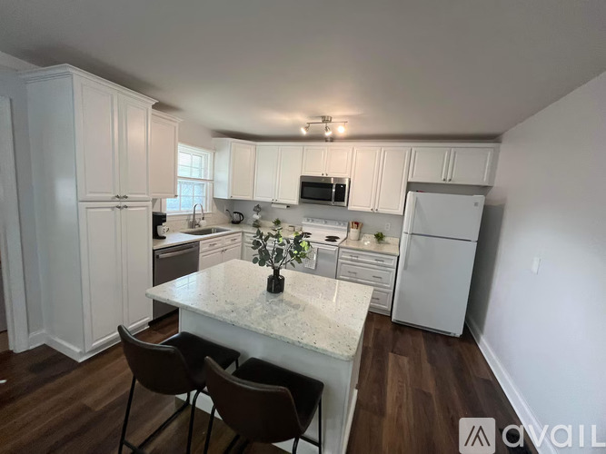 A kitchen with white cabinets and a marble countertop.