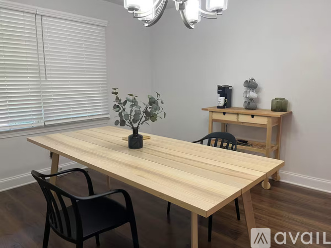 A wooden table with two chairs and a vase with a plant on it.