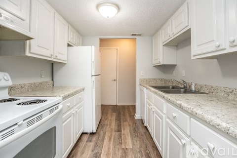 A kitchen with white cabinets and a white stove top oven.