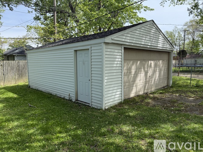 A small white shed with a closed door and a closed garage door.