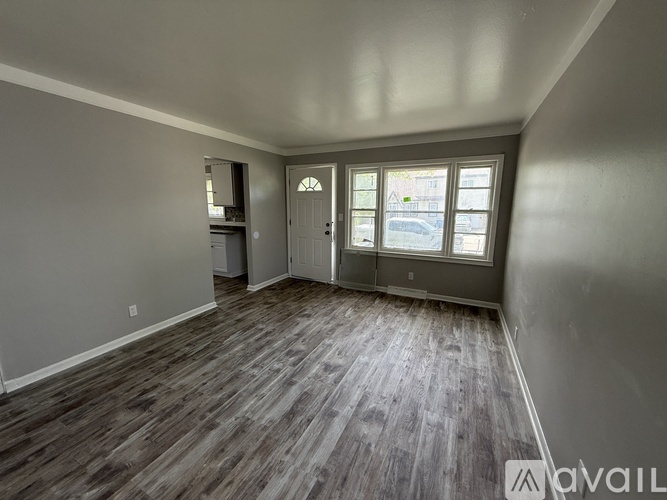 A room with wooden flooring and a window overlooking a street.