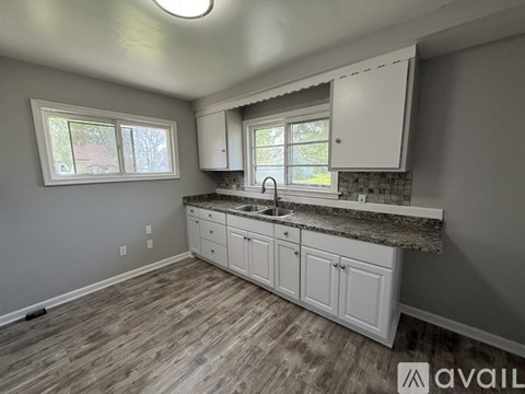 A kitchen with white cabinets and a granite countertop.