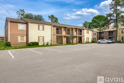 A parking lot in front of a row of apartment buildings.