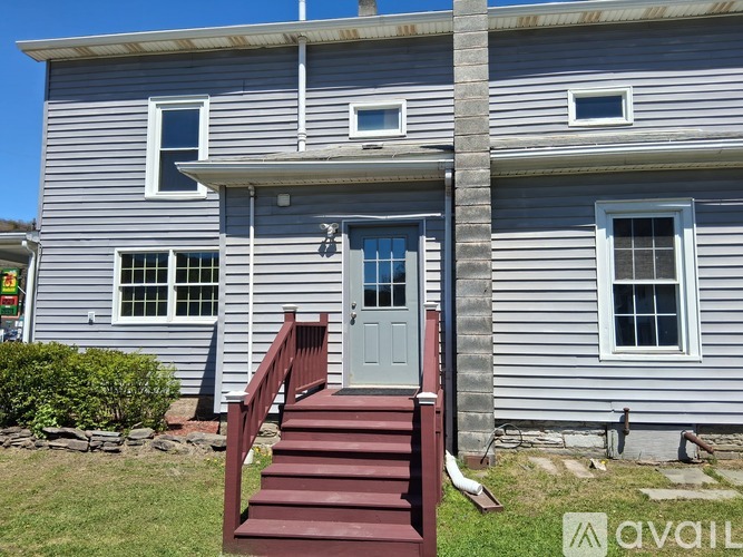 A house with a grey exterior and a red staircase leading to the front door.