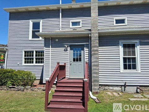 A house with a grey exterior and a red staircase leading to the front door.