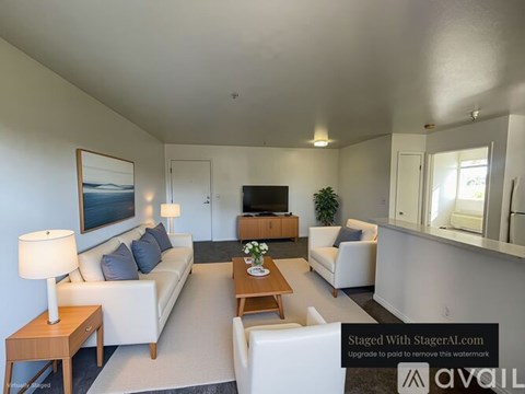 A living room with a white couch, a wooden coffee table, and a painting on the wall.