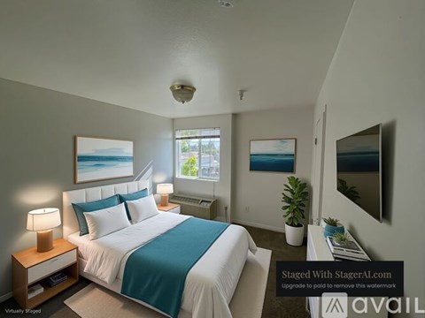 A bedroom with a bed, nightstand, and a window.