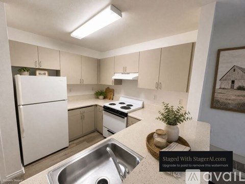 A kitchen with a white fridge, stove, and sink.