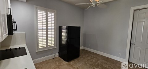 A kitchen with a black refrigerator and a fan.