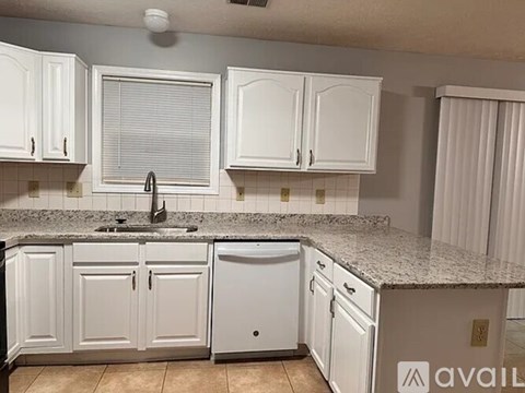 A kitchen with white cabinets and a granite countertop.