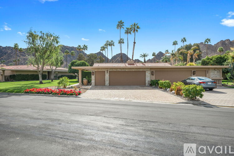 A house with a driveway and palm trees in the background.
