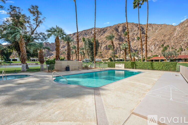 A pool surrounded by palm trees and a mountain in the background.