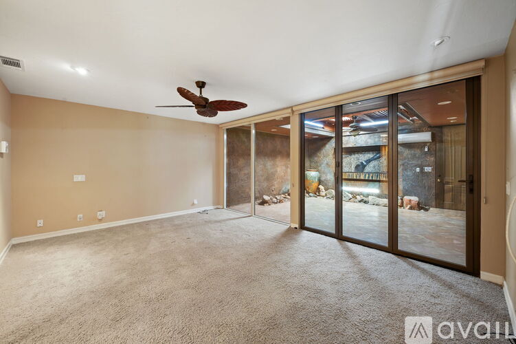 A spacious room with a ceiling fan and sliding glass doors leading to a view of a construction site.