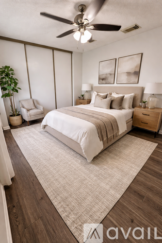 A bedroom with a large bed, a ceiling fan, and a chair.