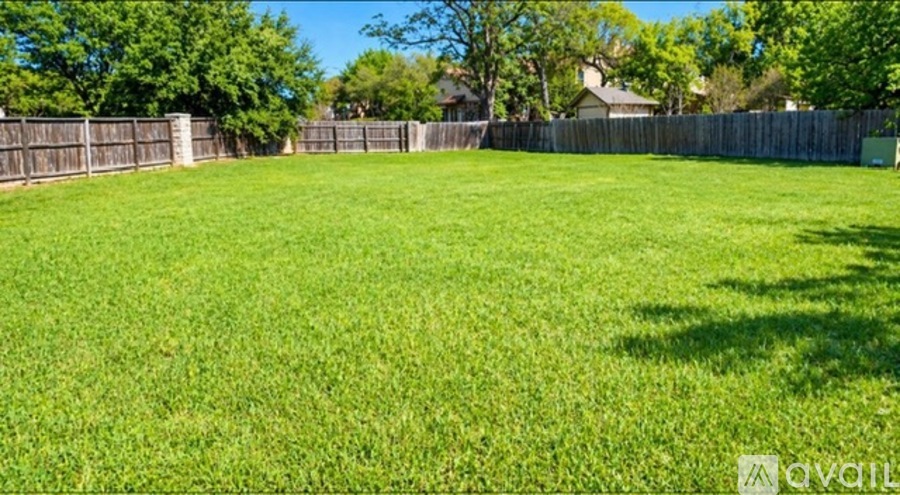 A grassy field with a fence in the background.