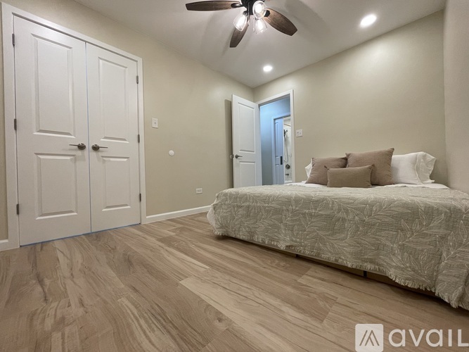 A bedroom with a bed, two doors, and a ceiling fan.