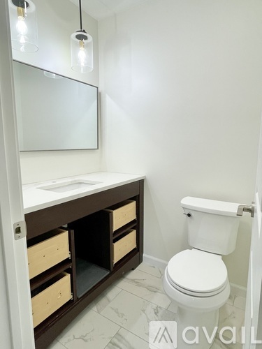A white toilet sits next to a sink with a mirror above it.
