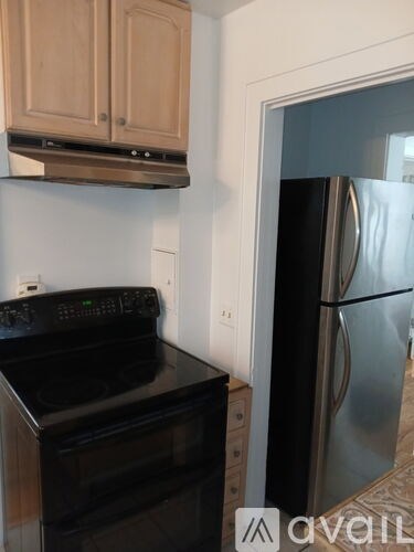 A kitchen with a black stove top oven and a stainless steel refrigerator.
