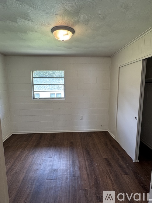 A room with a window and wooden floors.