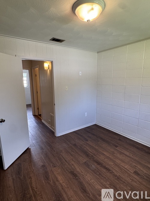 A room with a white door and a brown floor.