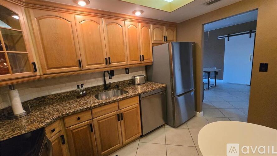 A kitchen with wooden cabinets and a stainless steel refrigerator.