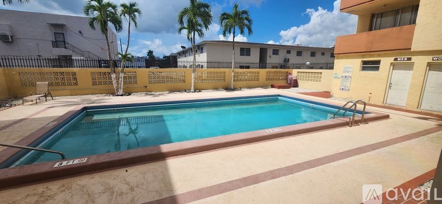 A small pool surrounded by a fence and palm trees.